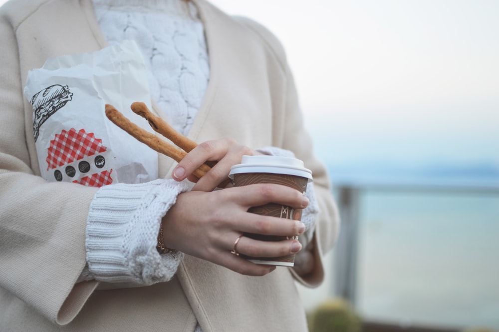 personne tenant une tasse de café