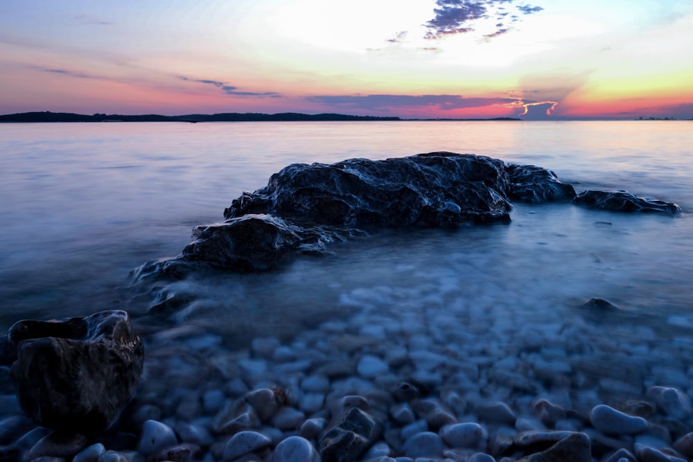 black rock surrounded with body of water