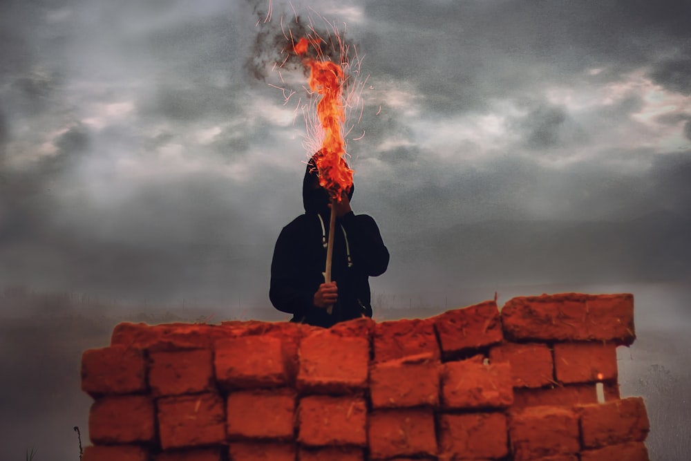 man holding torch light standing on red concrete rooftop