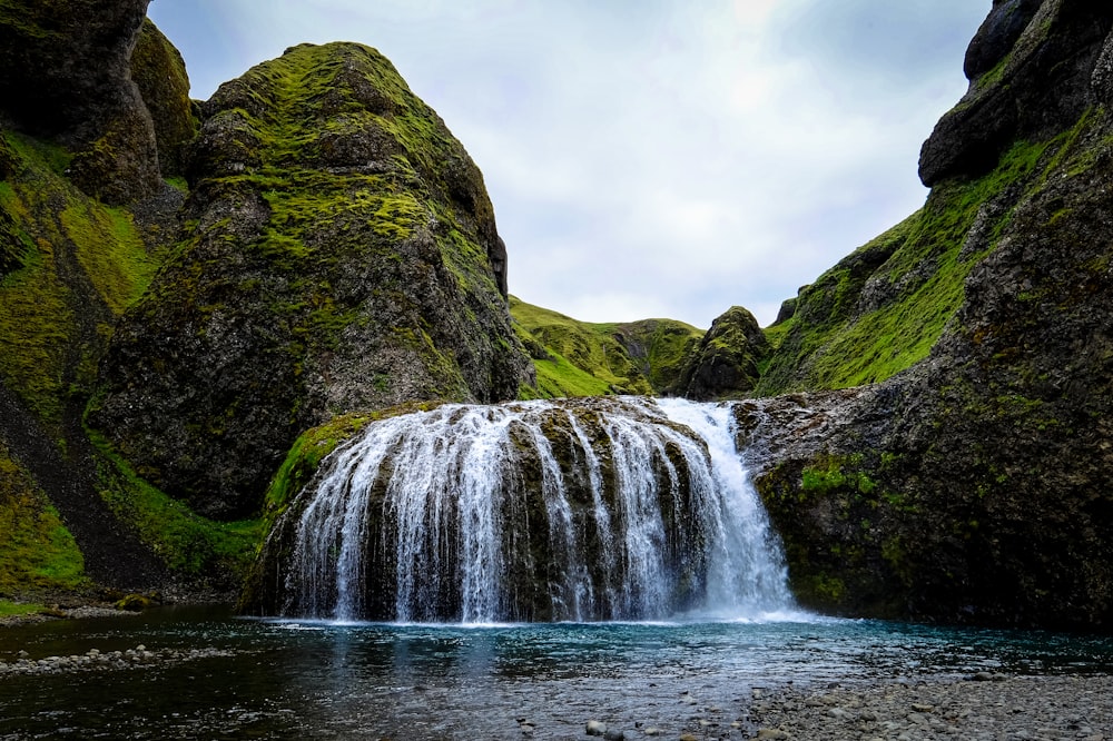 waterfalls near grass mountain range