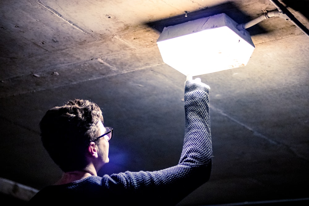 man holding lighted ceiling light