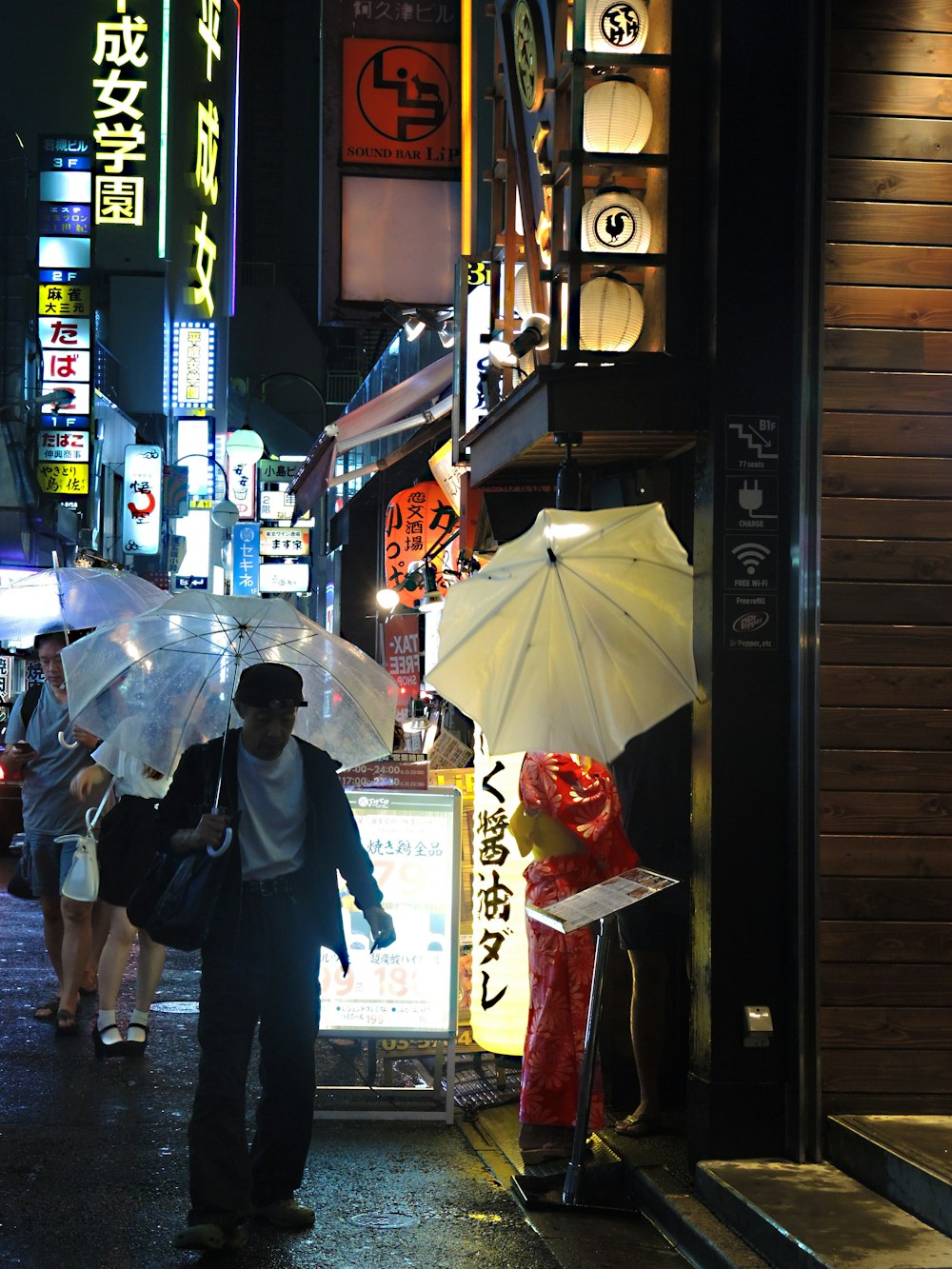 man in black jacket holding umbrella walking on street during nighttime