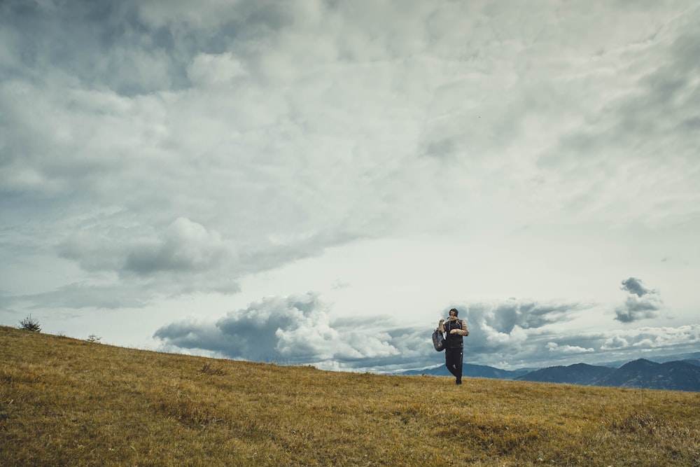 man on green grass field under white cloudy sky