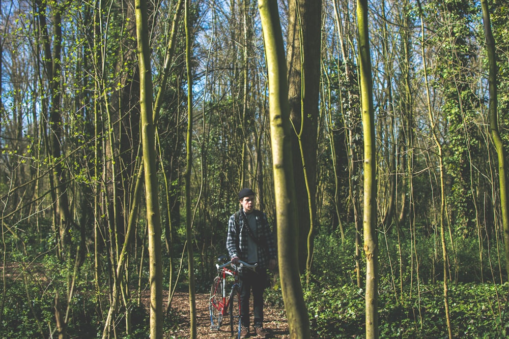 Fotografia de paisagem do homem segurando sua bicicleta na floresta