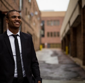 smiling man standing between brown concrete buildings at daytime