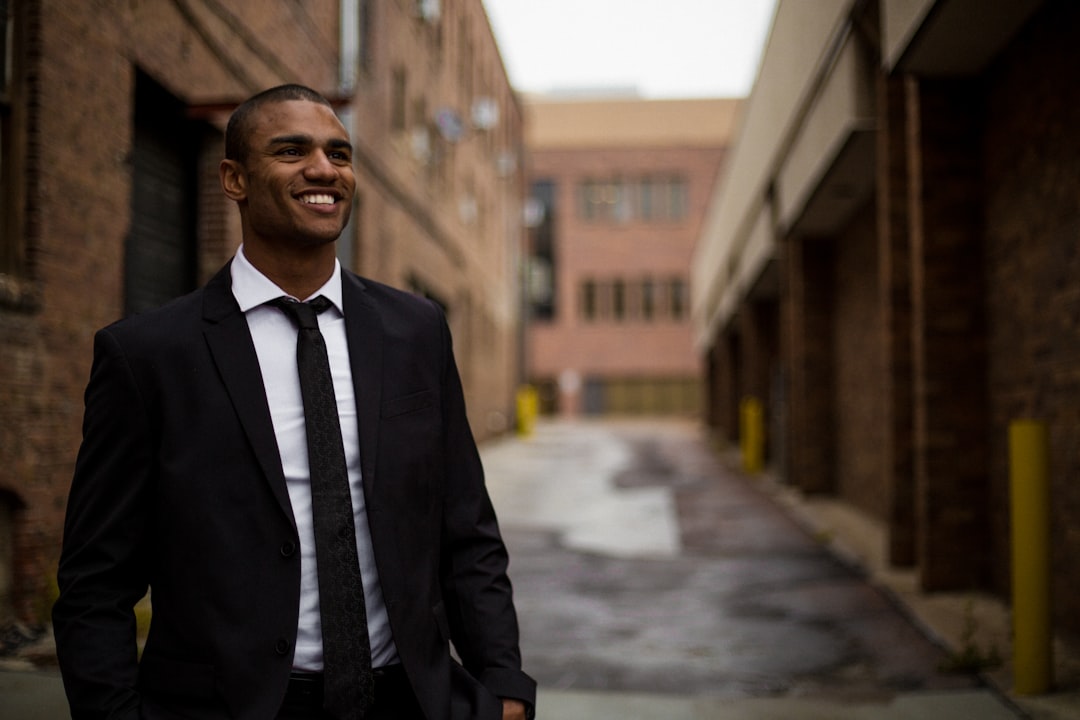 smiling man standing between brown concrete buildings at daytime credit union loans