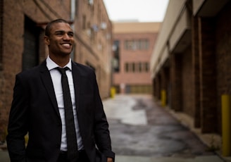 smiling man standing between brown concrete buildings at daytime