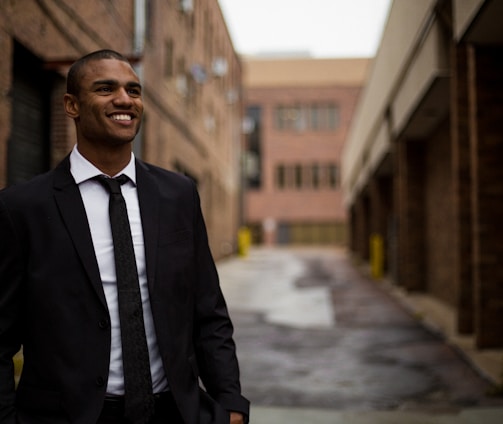 smiling man standing between brown concrete buildings at daytime