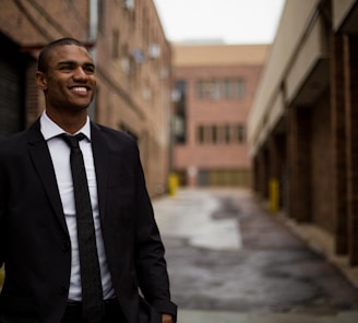 smiling man standing between brown concrete buildings at daytime