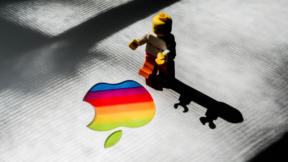 LEGO mini fig beside rainbow Apple logo