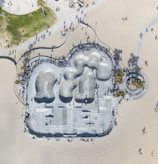 An aerial view captures a large concrete skatepark adjacent to a sandy beach. The park features smooth, curving bowls and ramps surrounded by numerous people casting long shadows. The layout includes paths and greenery nearby, along with palm trees and a promenade.