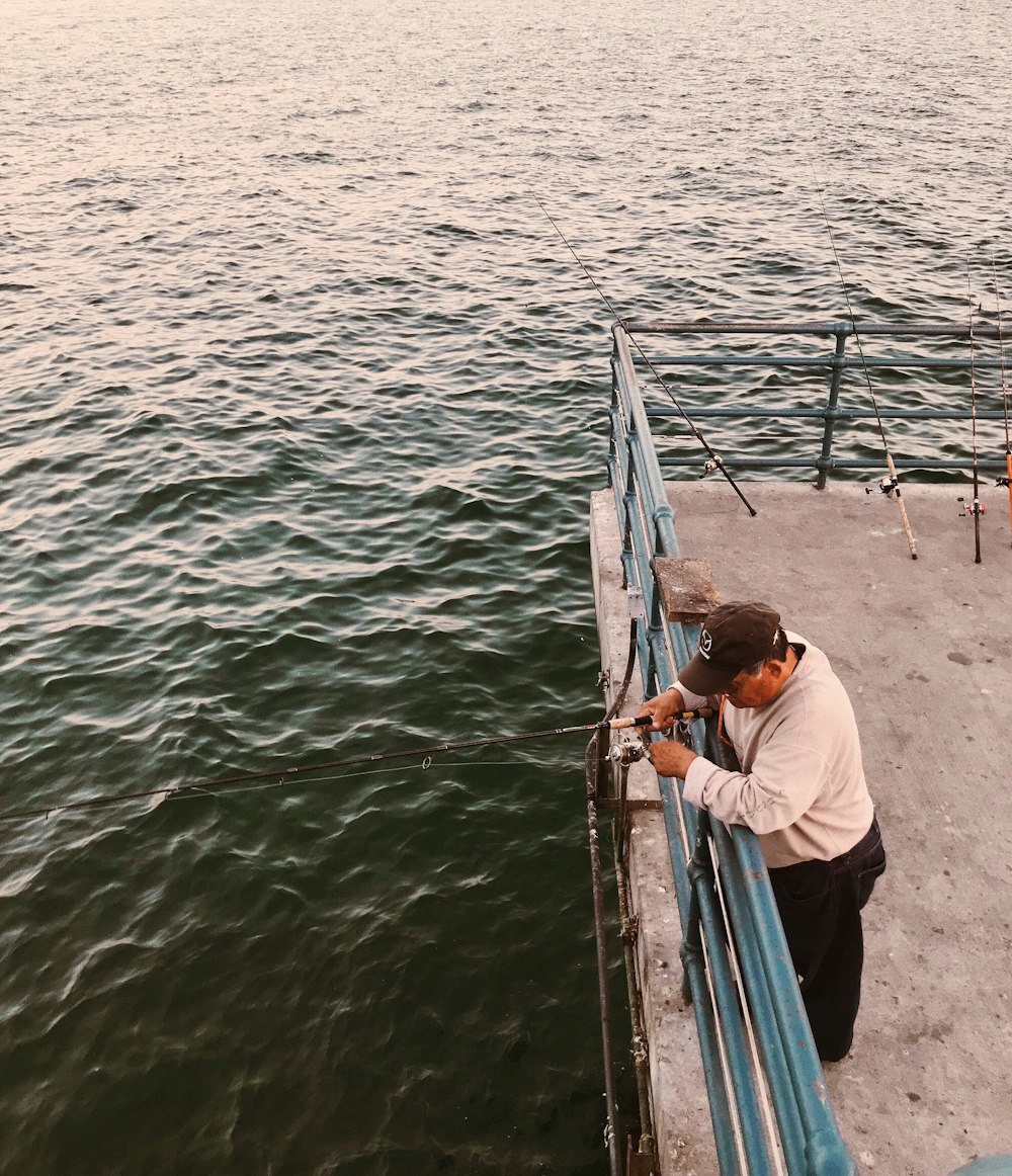 man holding black fishing rod standing on boat deck at daytime