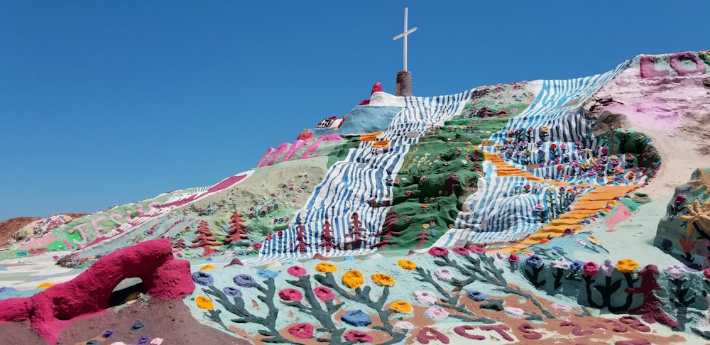 cross on top of multicolored hill