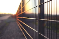 Evening view of a farm with metal fencing casting long shadows over the land.