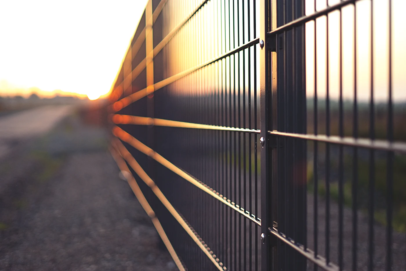 Metal fence posts silhouetted at sunset