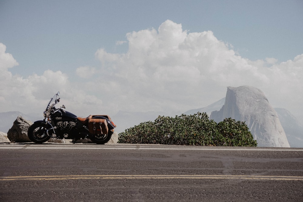motocicleta cruzadora preta ao lado de uma estrada preta