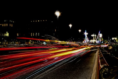 timelapse photography of vehicle lights crossing on road near city during nighttime