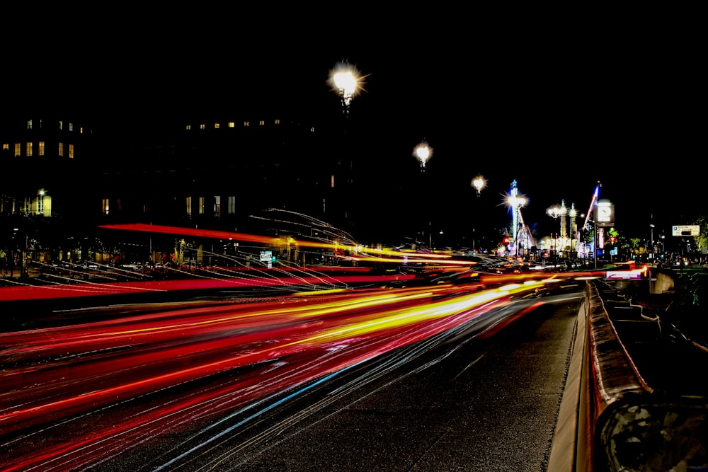 Photographie en accéléré des feux de véhicules traversant sur la route près de la ville pendant la nuit