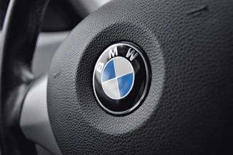 Close-up of a sleek BMW steering wheel with the iconic blue and white logo.