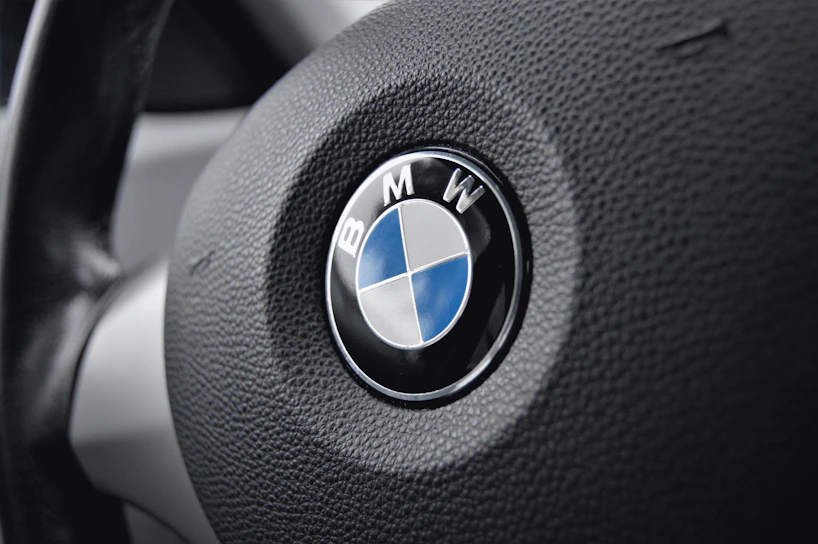 Close-up of a sleek BMW steering wheel with the iconic blue and white logo.