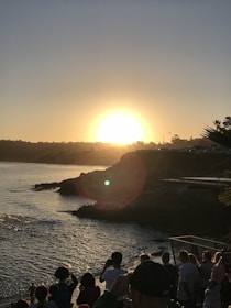 Group of travelers admiring a stunning coastal sunset with cliffs and sea.