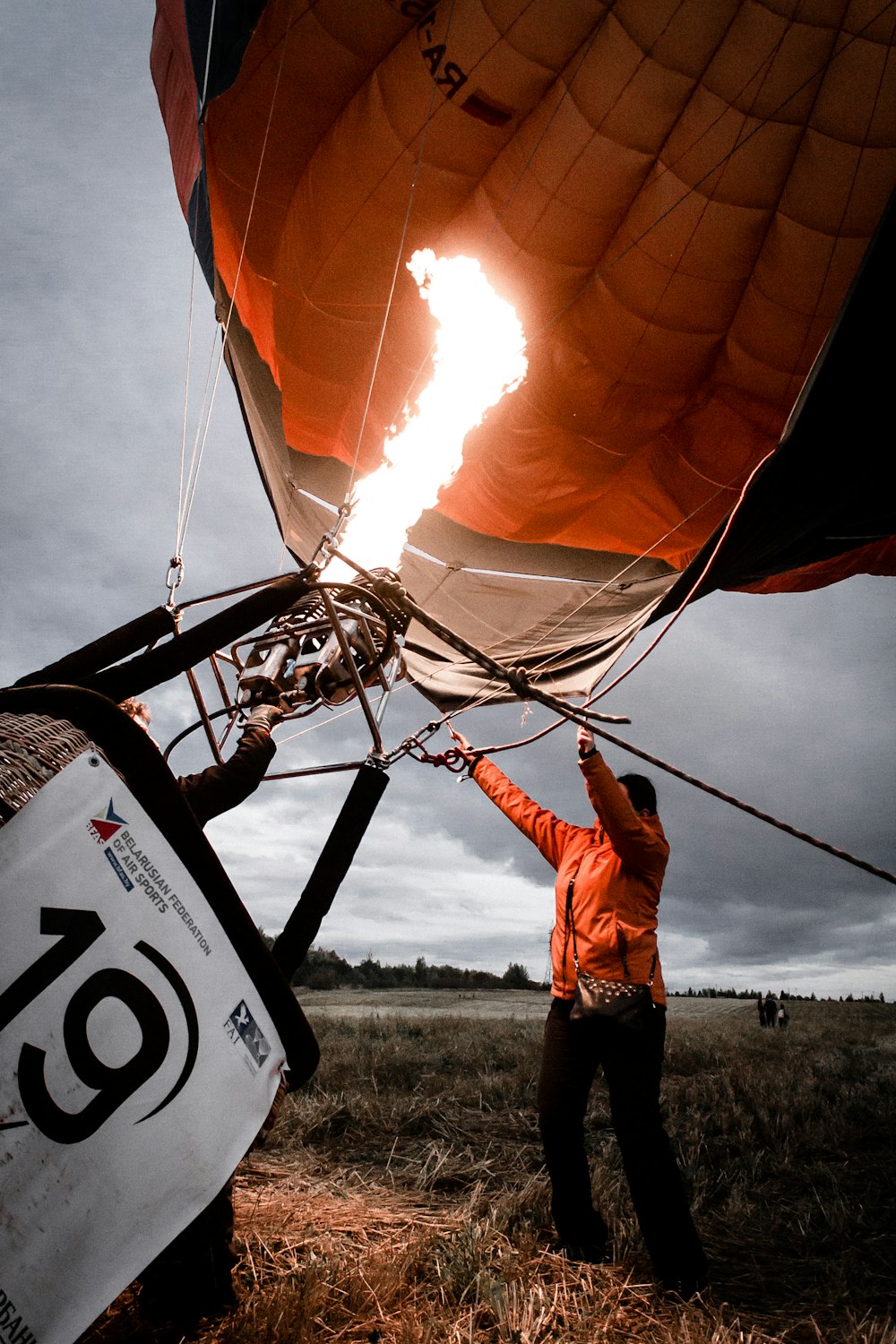 personne arrangeant une montgolfière orange et noire pendant la journée