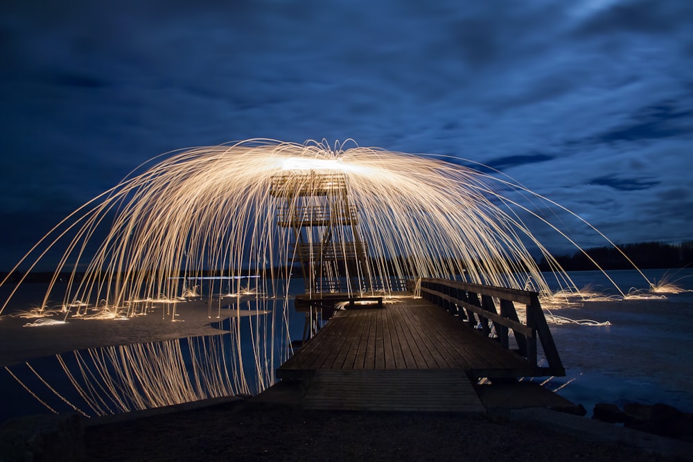 Exhibición de fuegos artificiales cerca del muelle de madera negra por la noche