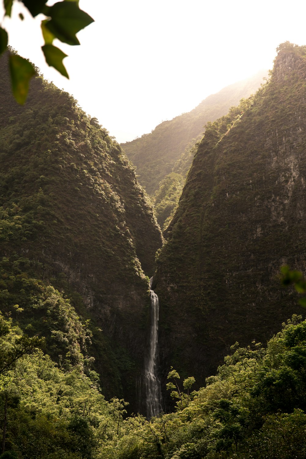 waterfalls between green mountains at daytime