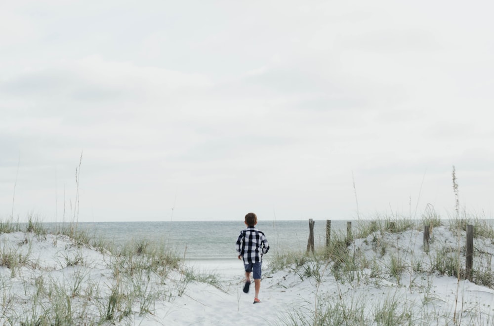 boy running near body of water