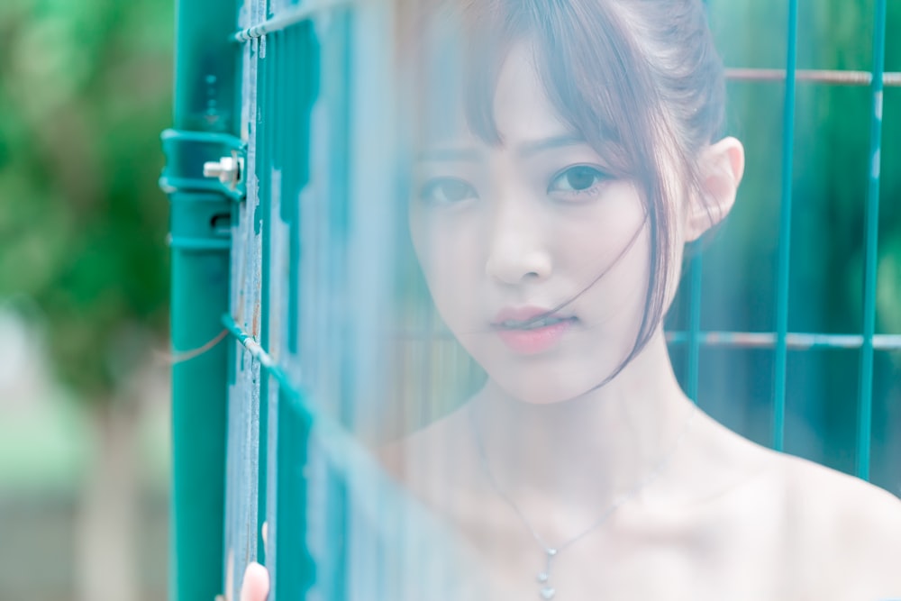 selective focus of woman face beside fence during daytime