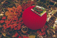 A vibrant blue knitted pouf adding a pop of color to a modern lounge area.