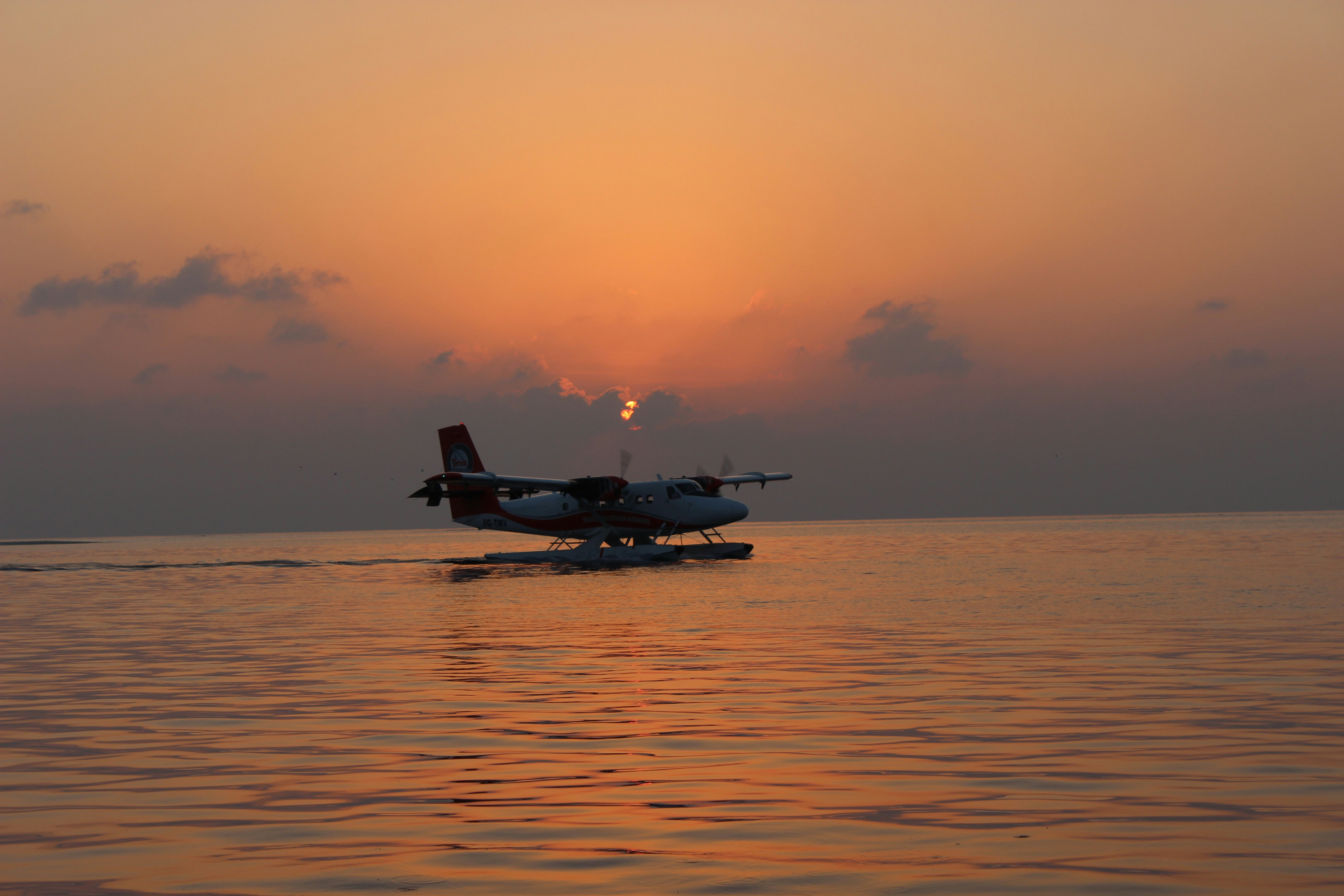 silhouette of plane on top of body of water during sunset, A seaplane in the Maldives.