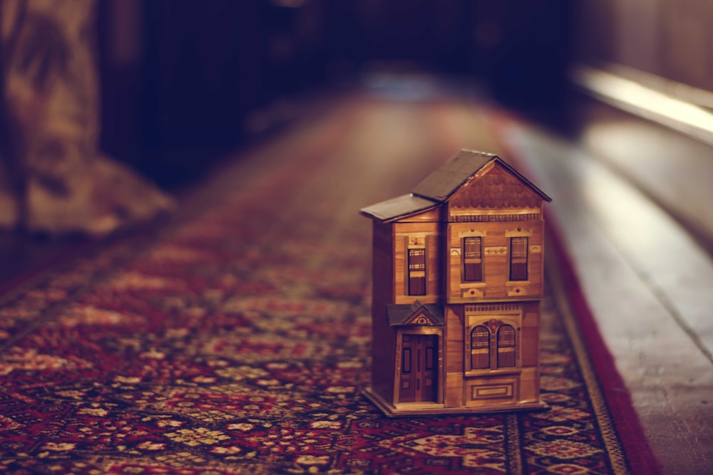Casa di legno marrone in miniatura sul tappeto rosso