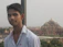 Smiling young man standing in front of an ancient Indian temple at sunset.