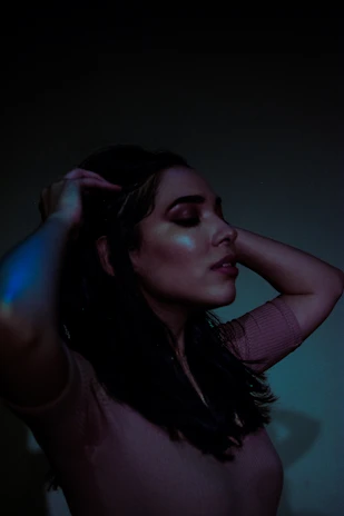 A serene woman enjoying a moment of self-care in a softly lit, minimalist room.