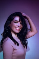 A woman smiling while touching her vibrant hair.