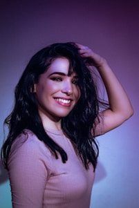 Close-up of a smiling person gently touching their healthy hair, symbolizing hair regrowth success.