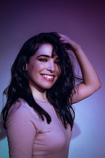 A woman smiling while touching her vibrant hair.