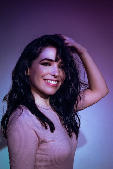 Close-up of a smiling person gently touching their healthy hair, symbolizing hair regrowth success.