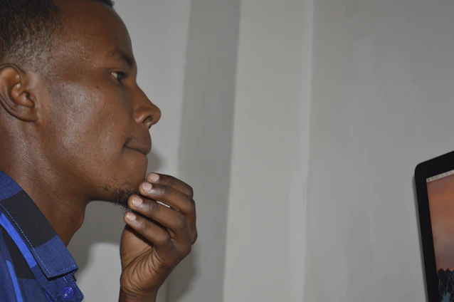A thoughtful man reading a laptop screen with a concerned expression, symbolizing awareness and caution.