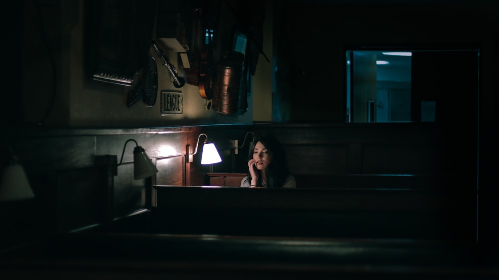 uma mulher sentada em uma pia em um quarto escuro