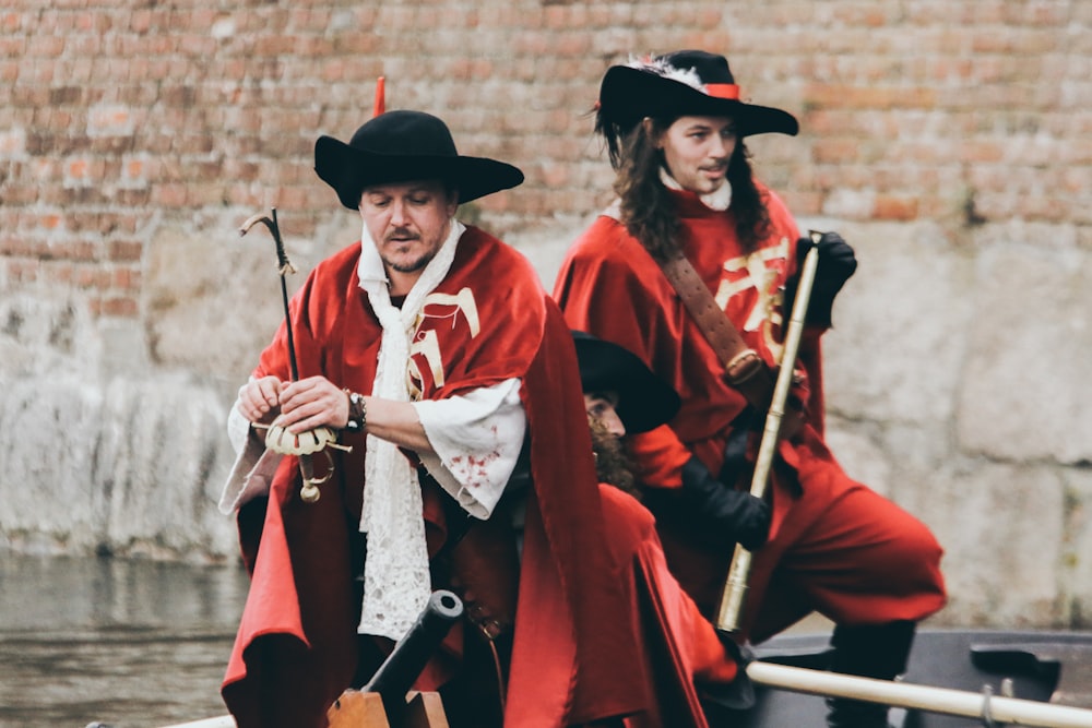 two men in red capes standing near brick wall