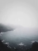 A misty coastal horizon where ocean meets sky in gentle embrace.