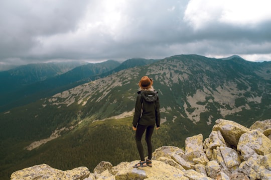 woman standing on rock facing mountains in Retezat National Park Romania