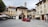 A rustic village center with people gathering near a community parcel delivery spot on a sunny day.