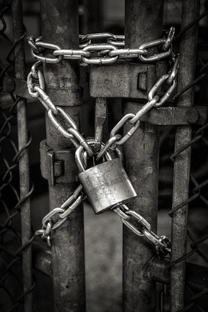 A heavy chain and padlock securing a metal gate, representing the closed APIs and blocked crawlers that keep AI agents out of customer comment data