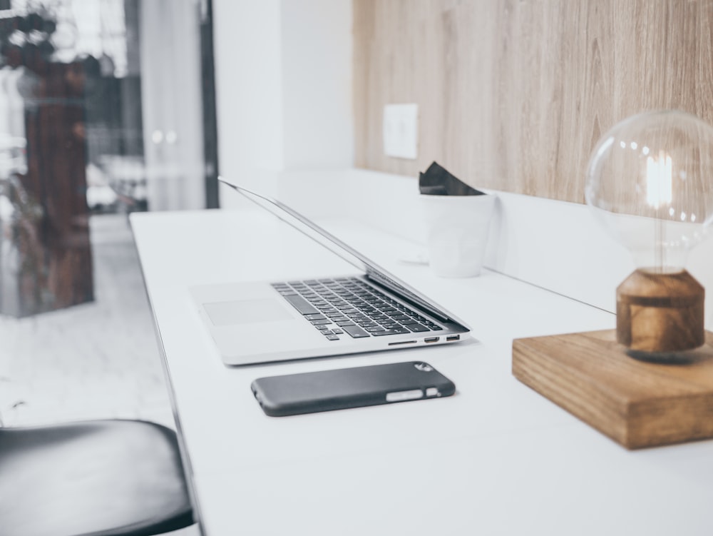 silver MacBook Pro on white table