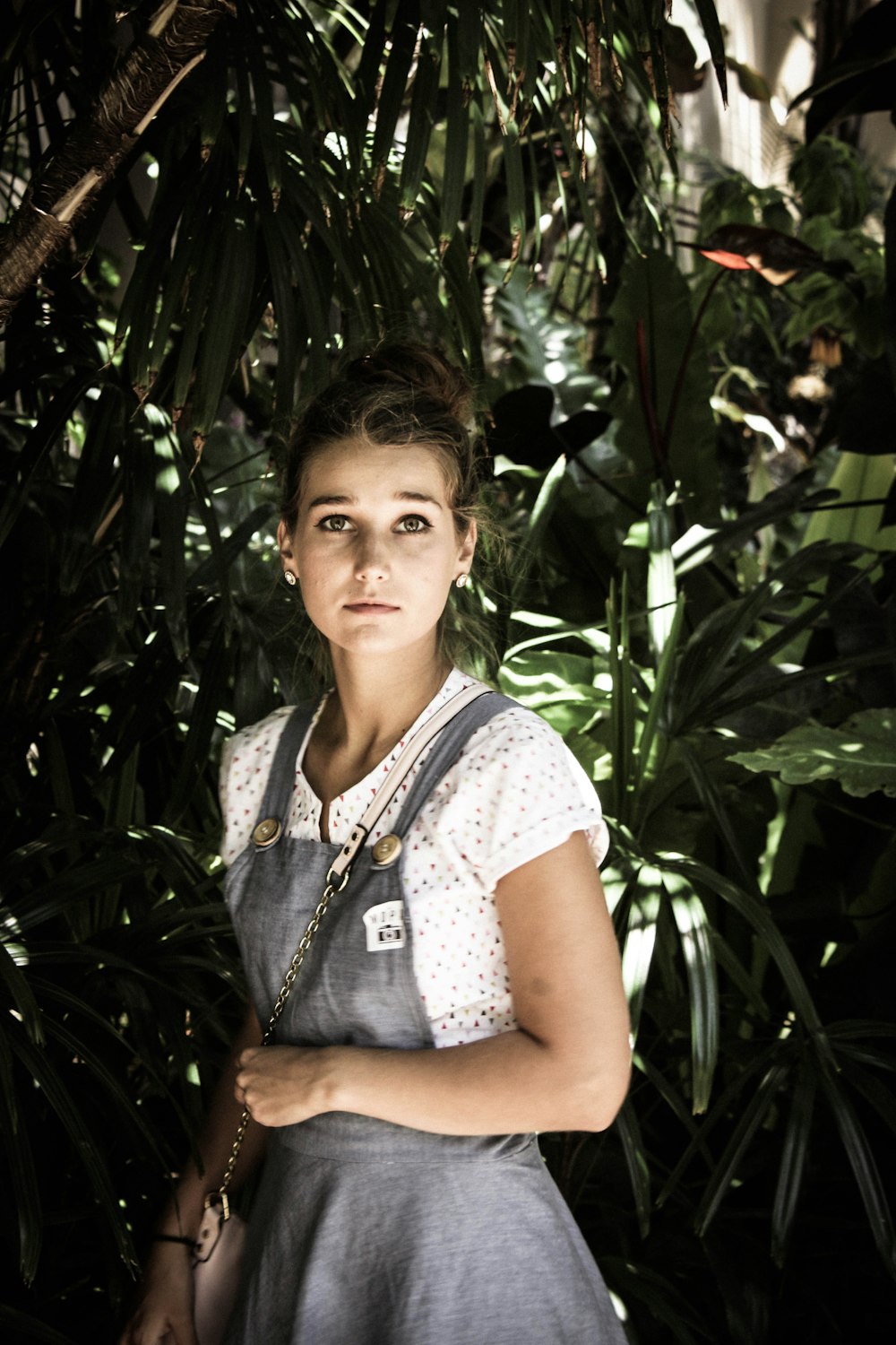 woman in gray and white dress standing beside green trees