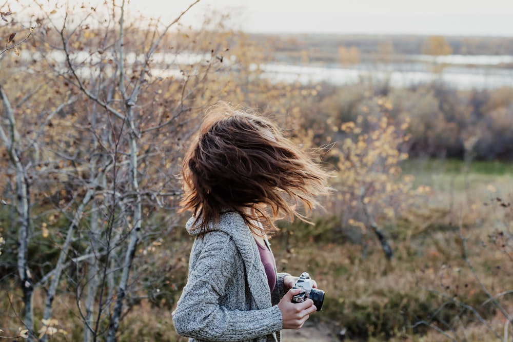 photo of woman waving her hair while holding camera