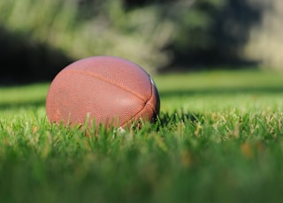 selective focus photography of brown football on grass at daytime